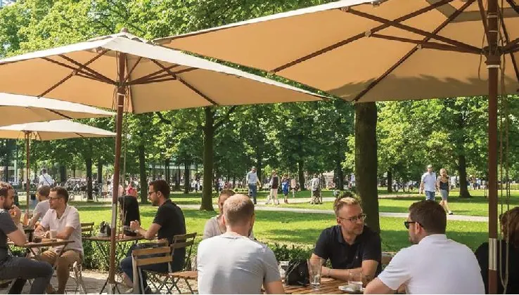 People at a café under parasols in a green park